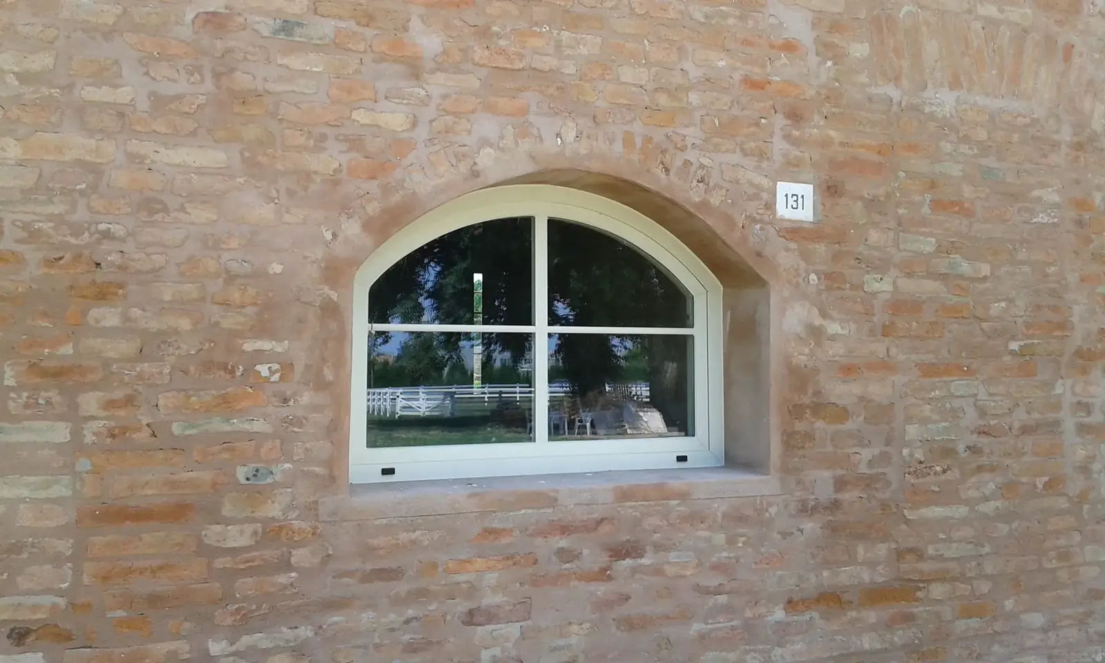 Serramento in legno ad arco su facciata in mattoni a vista
